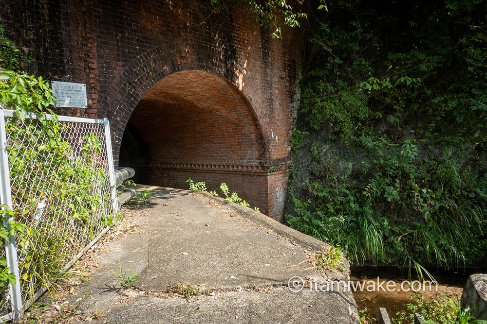 川にかかるトンネルの上を走る鉄道